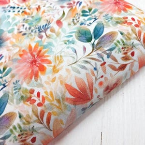 Tela de jersey floral con estampado de acuarela en tonos melocotón, naranja y salvia. Tejido de punto elástico de 150 cm de ancho, material de costura por medio metro.