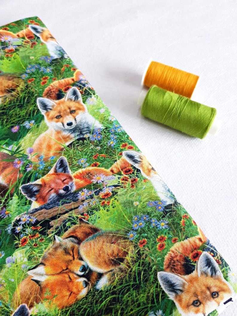 May include: A colorful fabric with a repeating pattern of red foxes sleeping in a field of green grass and wildflowers. The foxes are surrounded by blue, purple, and orange flowers.