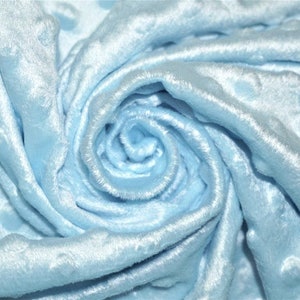 Op de afbeelding: Close-up van een lichtblauwe stof met een textuur van bubbels. De stof is zacht en pluche en perfect voor het maken van dekens, kussens of andere woonaccessoires.