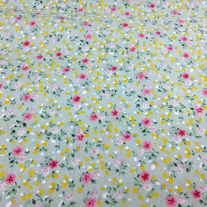 May include: A light green fabric with a small floral print. The print features pink and yellow flowers on a light green background.