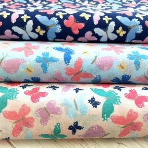 May include: Three fabric swatches with a butterfly print. The top swatch is navy blue with white, yellow, and pink butterflies. The middle swatch is light blue with pink, white, and yellow butterflies. The bottom swatch is cream with pink, purple, and teal butterflies.