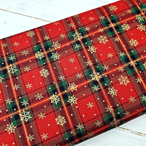 Könnte beinhalten: Roter und grüner karierter Stoff mit einem goldenen Schneeflockenmuster. Der Stoff ist perfekt für Weihnachtsbastelarbeiten und Projekte.