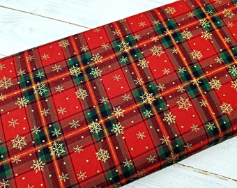 May include: Red and green plaid fabric with a gold snowflake pattern. The fabric is perfect for holiday crafts and projects.