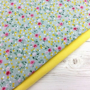May include: A close-up of two fabric swatches. The top swatch is a light gray fabric with a small pink and yellow floral print. The bottom swatch is a solid yellow fabric.