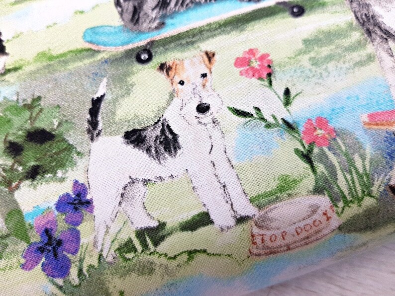 May include: Fabric with a dog-themed print. The design features a white and brown dog standing near a dog bowl with the text "TOP DOG". Other dogs are shown with a skateboard and flowers in a park setting. The color palette includes green, blue, and pink.
