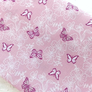 May include: Pink fabric with a white floral pattern and pink butterflies printed on it.