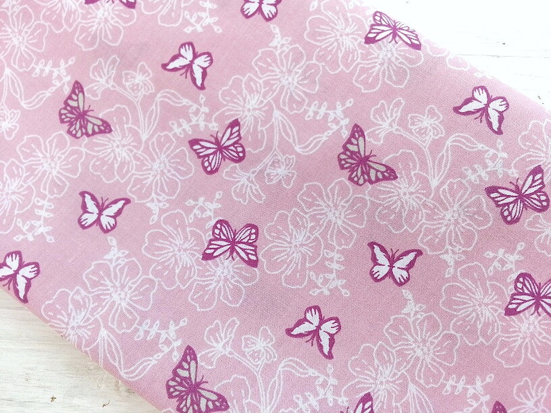 May include: Pink fabric with a white floral pattern and pink butterflies printed on it.