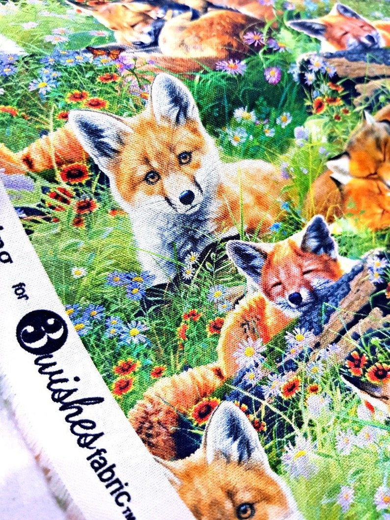 May include: A colorful fabric with a repeating pattern of foxes in a field of flowers. The foxes are orange, white, and brown, and the flowers are pink, purple, yellow, and red. The fabric has a white border with the text "Brushes Fabric" printed on it.