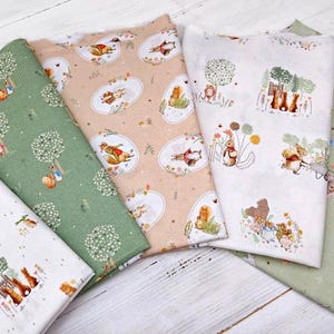 Puede incluir: Cuatro muestras de tela diferentes con un tema de animales del bosque. Las telas son en tonos de verde, blanco y beige. Los animales incluyen ardillas, conejos y pájaros.