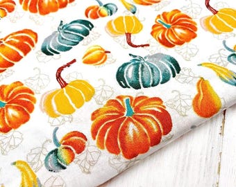 May include: White fabric with a repeating pattern of orange, yellow, and teal pumpkins and gourds. The pumpkins have red stems and are in various sizes. The fabric has a fall harvest theme.