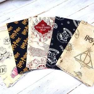 May include: Five fabric items with Harry Potter designs. The fabrics display the Marauder's Map, Hogwarts crest, Platform 9 3/4, and the Harry Potter logo. The color scheme includes black, cream, and red. The items are arranged in a fan shape.