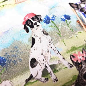May include: Fabric featuring a whimsical illustration of dogs in a park setting. A Dalmatian wearing a red cap is the focal point, surrounded by other dogs, blue flowers, and a light blue and green background.