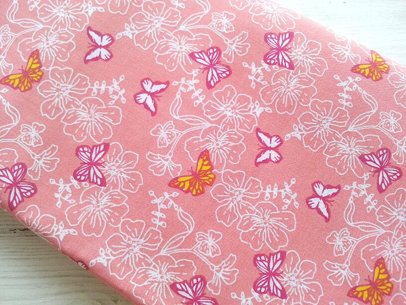 May include: Pink fabric with a white floral pattern and colorful butterflies. The fabric is perfect for crafting projects, quilting, and sewing.