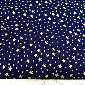 May include: Dark navy blue fabric with a repeating pattern of gold stars. The stars vary in size and are scattered across the material. A ruler with inch measurements is at the bottom of the image.