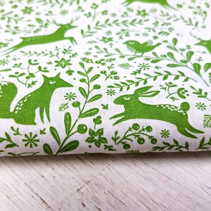 K&ouml;nnte beinhalten: Gr&uuml;ner Stoff mit wei&szlig;em Hintergrund und einem sich wiederholenden Muster aus F&uuml;chsen, Rehen, Kaninchen, V&ouml;geln und Blumenmotiven.