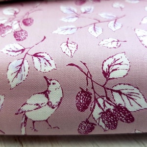Op de afbeelding: Roze stof met een wit en bordeauxrood bloemenpatroon met vogels en bessen.