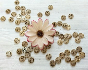 May include: A collection of decorative wooden buttons with intricate designs, arranged around a single pink flower with a brown center.