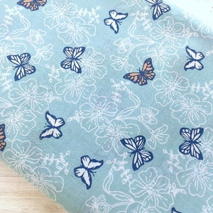 May include: A light blue fabric with a white floral pattern and a repeating design of orange and blue butterflies.
