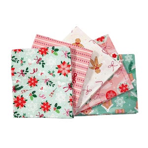 Könnte beinhalten: Ein Set aus fünf gefalteten Stoffquadraten mit weihnachtlichen Mustern. Die Designs umfassen rote Weihnachtssterne auf hellgrünem Grund, rosa-weiße Diagonalstreifen, Lebkuchenmänner auf cremefarbenem Grund, rosa Christbaumkugeln sowie grüne Tannenzweige mit Schneeflocken.