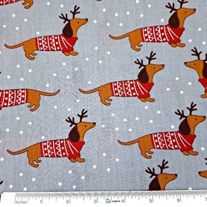 May include: A gray fabric with a white polka dot pattern featuring a repeating design of brown dachshunds wearing red and white reindeer sweaters.