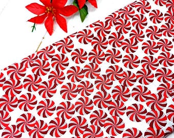 Könnte beinhalten: Weißer Stoff mit einem sich wiederholenden Muster aus roten und kastanienbraunen Wirbeln. Zwei rote Poinsettienblüten mit grünen Blättern befinden sich in der oberen linken Ecke. Für Weihnachtsdekorationen.