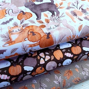 Puede incluir: Tres rollos de tela plegados con patrones de Halloween. La capa superior muestra gatos, calabazas y lápidas con el texto RIP. La capa intermedia muestra calabazas, dulces de maíz y fantasmas sobre marrón. La capa inferior muestra hojas de otoño.