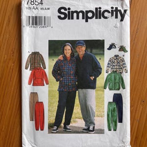 May include: A Simplicity sewing pattern envelope 7854 for size AA XS,S,M. The white paper envelope features illustrations and photographs of hooded jackets and trousers in various colours and patterns, including plaid, solid red, green, and grey.