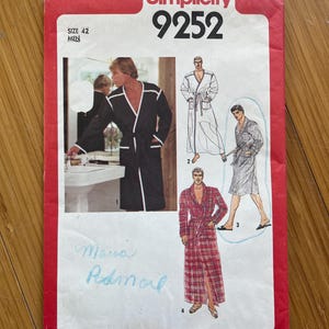 May include: Simplicity sewing pattern number 9252 for a robe. The pattern includes four different styles of robes, including a black robe with white piping, a white robe with white piping, a red and white plaid robe, and a white robe with a black trim. The pattern is for size 42 men.