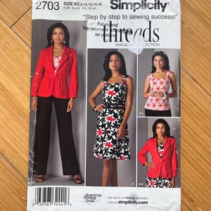 Op de afbeelding: Simplicity naaipatroon 2703. Het patroon toont een vrouw in een rode blazer en zwarte broek, een bloemenjurk en een roze en witte top. Het patroon bevat de tekst "Step by step to sewing success!"