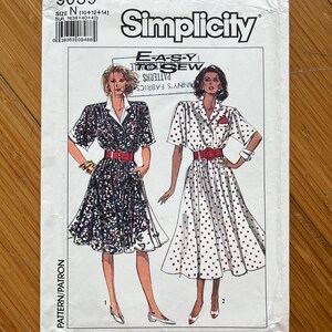 May include: Simplicity sewing pattern number 9039, size N (10-12-14), for a dress with a collared neckline, short sleeves, and a gathered skirt. The pattern includes two different views, one with a floral print and the other with polka dots. The pattern is labelled "Easy to Sew" and "Any's Fabrics".