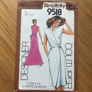 Peut inclure: Un patron de couture Simplicity 9518 vintage avec une robe de créateur. La couverture du patron montre des illustrations de la robe en blanc et rose. Le texte comprend "Designer" et "Cathy Hardwick."