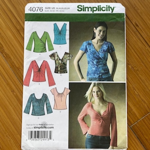 Peut inclure: Patron de couture Simplicity 4076. Le patron présente des illustrations de hauts de style cache-cœur en vert, bleu, rouge et sarcelle. Le patron comprend les tailles U5 16, 18, 20, 22, 24 et EUR 42-50, FR 44-52. Le logo Simplicity est en haut.