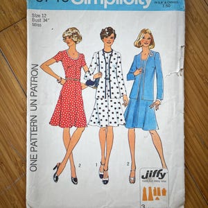 Pode incluir: Padrão de costura vintage Simplicity número 6749 para um vestido. O padrão é para o tamanho 12, busto 86 cm, e é para mulheres. O padrão inclui três estilos de vestidos diferentes, um com bolinhas, outro com um padrão de bolinhas vermelho e branco sólido, e outro com um tecido azul sólido. O padrão é rotulado como "Jiffy easy-cut-easy sew" e inclui três peças de padrão.