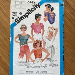 May include: Simplicity sewing pattern number 6412 for one-metre tops. The pattern features four different styles of tops with a variety of necklines and sleeve lengths. The pattern is for knit fabrics that have stretch.