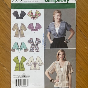 Pode incluir: Um padrão de costura Simplicity, tamanho U5, com vários designs de jaquetas. O padrão inclui ilustrações de diferentes estilos de jaquetas, com uma modelo vestindo uma jaqueta azul clara e uma jaqueta bege com acabamento em renda. O número do padrão é 2223.