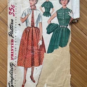 May include: Vintage Simplicity sewing pattern number 35c for a blouse and skirt. The pattern is printed on each pattern piece and includes sizes 16 and 34. The pattern features a woman wearing a white blouse with a red and white polka dot skirt.