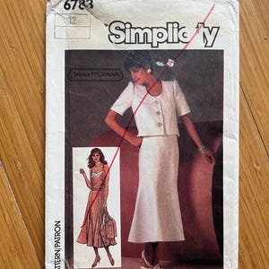 Pode incluir: Padrão de costura Simplicity número 6783 para uma saia e uma jaqueta. O padrão é para o tamanho 12 e inclui uma saia e uma jaqueta brancas com uma frente abotoada branca. O padrão está sobre um fundo branco com texto vermelho e preto.
