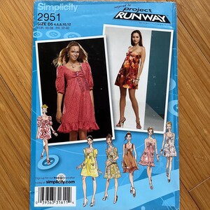 Puede incluir: Patrón de costura Simplicity número 2951, inspirado en Project Runway, para un vestido en tallas 4, 6, 8, 10 y 12. El patrón incluye múltiples vistas del vestido, con diferentes estilos y telas.