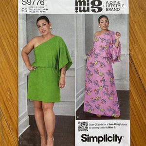 May include: A sewing pattern for a dress with a one-shoulder design. The pattern is for sizes UK 12-20, EU 38-46, and FR 40-48. The pattern is from Simplicity and is part of the mig brand. The pattern includes a QR code for a sew-along tutorial by Mimi G.