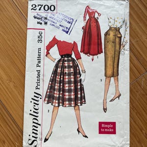Pode incluir: Envelope de padrão Simplicity vintage com ilustrações de saias e tops. O envelope é branco sujo com texto e ilustrações em vermelho e preto. O número 2700 está impresso no canto superior esquerdo. As palavras "Simple to make" estão em uma caixa rosa.
