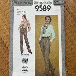 Peut inclure: Patron de couture Simplicity 9589 vintage. Le patron présente des illustrations de pantalons pour femmes. La couverture comprend du texte tel que « WAIST 67 CM » et « FUSS-FREE FIT ». Le patron est sur fond gris clair.