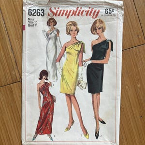 May include: A vintage Simplicity sewing pattern, showcasing illustrations of women in stylish dresses. The pattern cover displays the number 6263, with size and bust measurements. The design includes various one-shoulder and strapless dress styles.