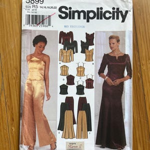 Puede incluir: Patrón de costura Simplicity número 5899 para las tallas R5 14, 16, 18, 20, 22. El patrón incluye instrucciones para hacer un vestido y unos pantalones. El vestido es un vestido largo y fluido con un escote en V. Los pantalones son de pierna ancha y tienen una cintura alta. El patrón está ilustrado con una mujer que lleva el vestido y una mujer que lleva los pantalones.
