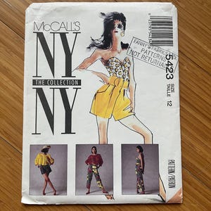 May include: Vintage McCall's NY sewing pattern. The package features a fashion illustration of a woman in a yellow shorts outfit. The text on the package reads "NY The Collection" and includes the size 12.