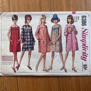 May include: A Simplicity sewing pattern envelope, number 6386, for a Miss size 12 dress with a 32-inch bust. The illustration displays five variations of a sleeveless or long-sleeved shift dress with pockets, smocking details, and collars.