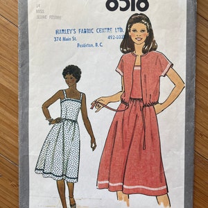 Può includere: Modello di cucito Simplicity numero 8518 per un abito. Il modello è per una signorina o una giovane donna. Il modello mostra due modelle che indossano l'abito. Una modella indossa un abito bianco con pois neri e l'altra modella indossa un abito rosa. Il modello include istruzioni per la realizzazione dell'abito.