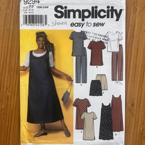 Könnte beinhalten: Ein Simplicity 9294 Schnittmusterumschlag für die Größen 18W-24W mit der Aufschrift Shawna easy to sew. Die Vorderseite zeigt ein Modell in einem dunklen ärmellosen Kleid über einem hellen T-Shirt sowie Illustrationen verschiedener Kleidungsstücke.