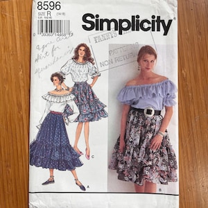 May include: A Simplicity sewing pattern envelope 8596, size R, featuring illustrations of off-the-shoulder ruffled tops and tiered skirts. The cover displays three variations of the outfit with different fabric patterns, including floral and gingham prints.
