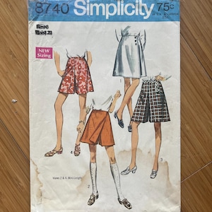 May include: Vintage Simplicity sewing pattern number 8740 for women's shorts. The pattern includes four different views, with a white, plaid, and two orange and red patterned shorts. The pattern is labelled "New Sizing" and "Mini-Length".