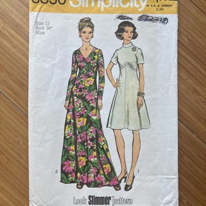 May include: Vintage Simplicity sewing pattern number 5850 for a dress. The pattern is for size 12 with a 34 inch bust. The pattern features two illustrations of women wearing dresses. One dress is a long, floral print dress and the other is a short, white dress. The pattern is labelled "Look Slimmer pattern".